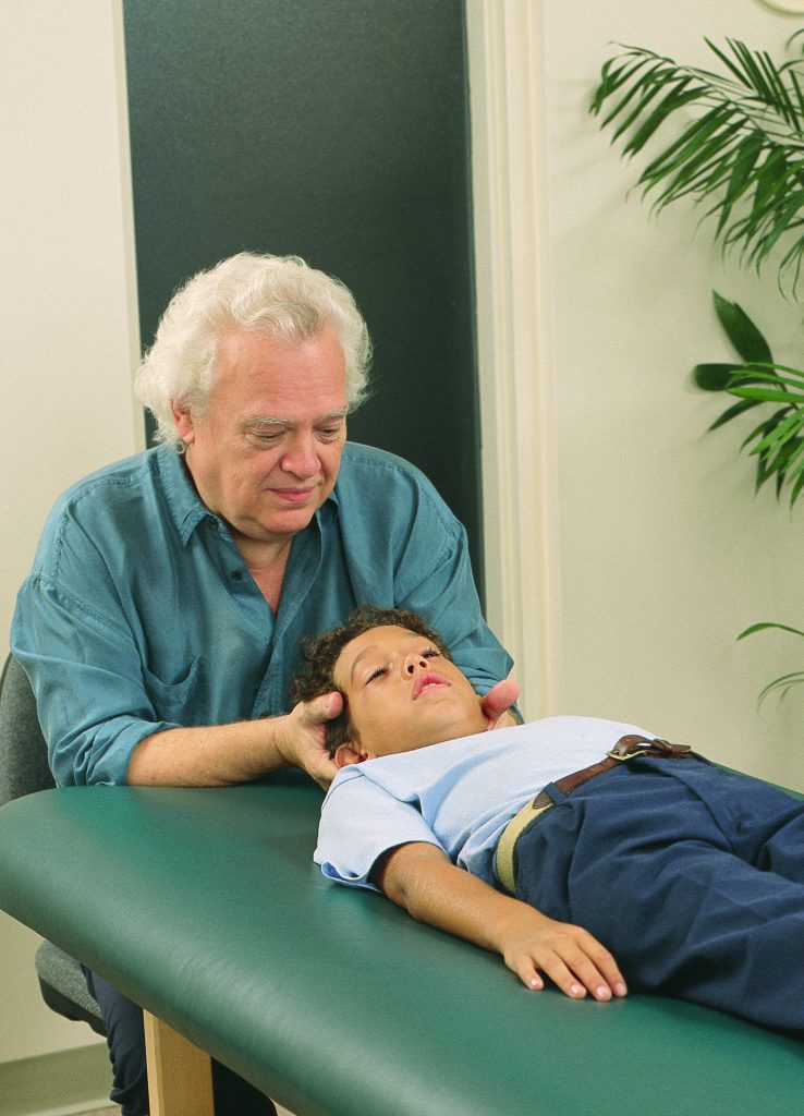 Therapeut hält den Kopf eines Jungen.